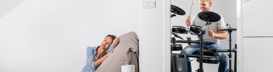 Muž hrající na bicí a v druhé místnosti klidně ležící žena cz