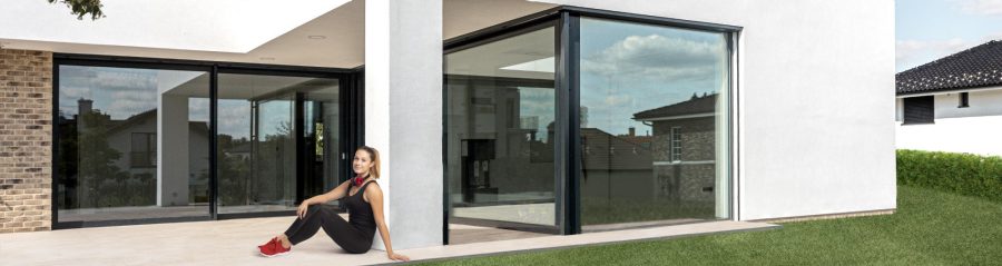 Žena sedící před domem na terase ve sportovním oblečení a se sluchátky | Újezd u Průhonic | Wienerberger e4 dům